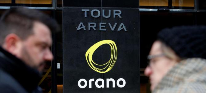 People walk past the new company name "Orano" of the French nuclear fuel group Areva installed on the Areva Tower in La Defense near Paris